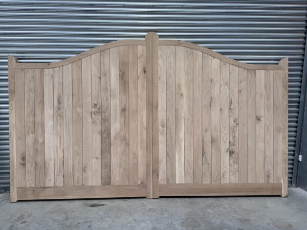 Wooden oak swan neck driveway gates leaning against metal shutters