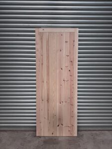 Super heavy duty full board wooden garage side door leaning against metal shutters