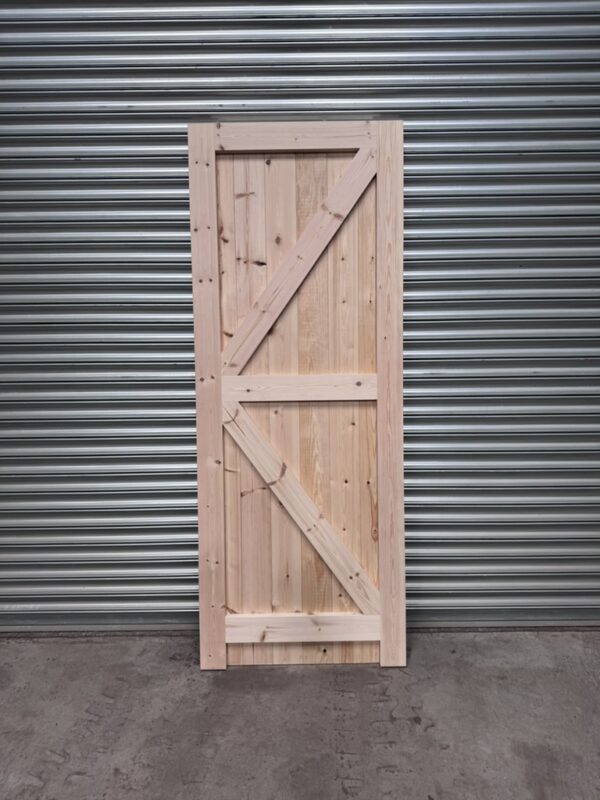 Interior detailing of a wooden full board side door leaning against metal shutter