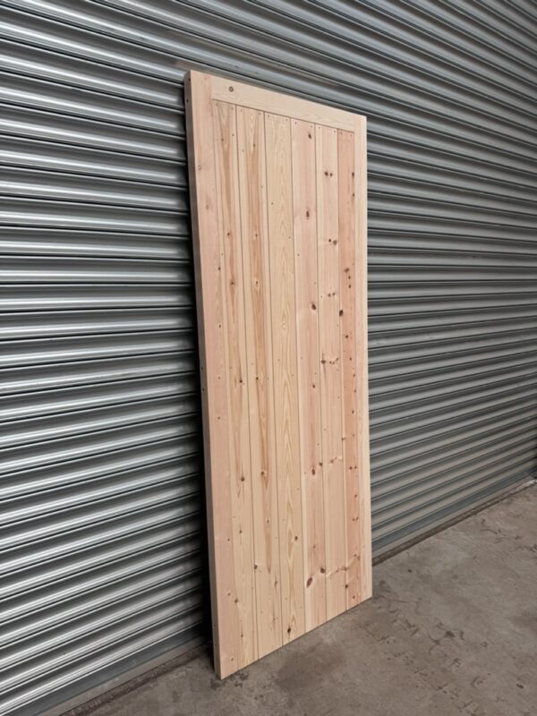 Super heavy duty wooden garage side door leaning against metal shutter