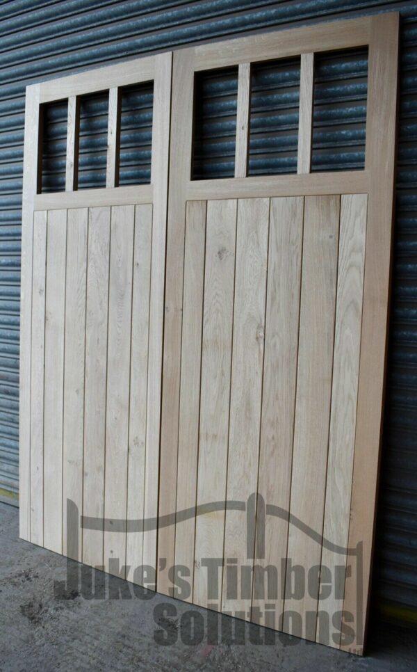 Wooden 6 pane oak garage doors pictured outside leaning against metal shutters