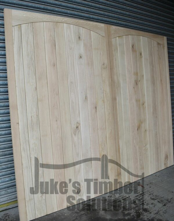 Hardwood garage door with curved detailing, leaning against metal shutters