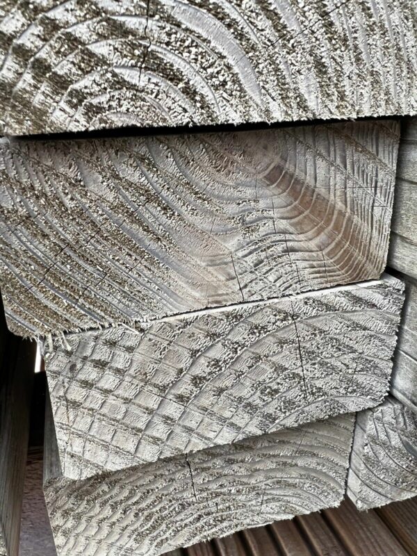 Close up of the end of tanalised CLS timber planks, stacked on top of one another.