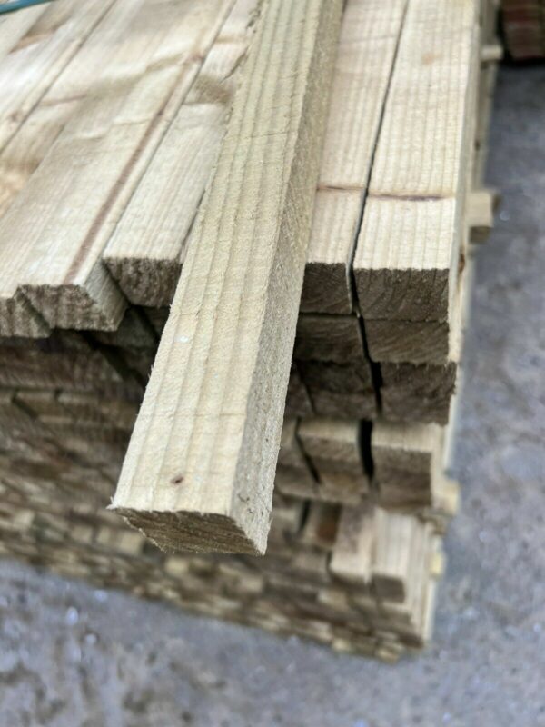 A length of tanalised timber, pulled out from a stack of wood.