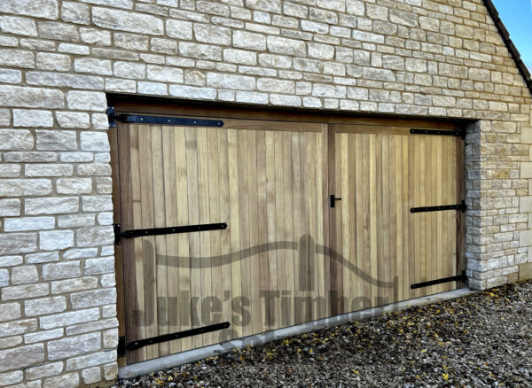 Overview of an iroko full board garage door, installed into a stone garage
