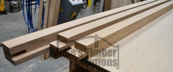 Lengths of wood making up an oak garage door frame, pictured on workbench
