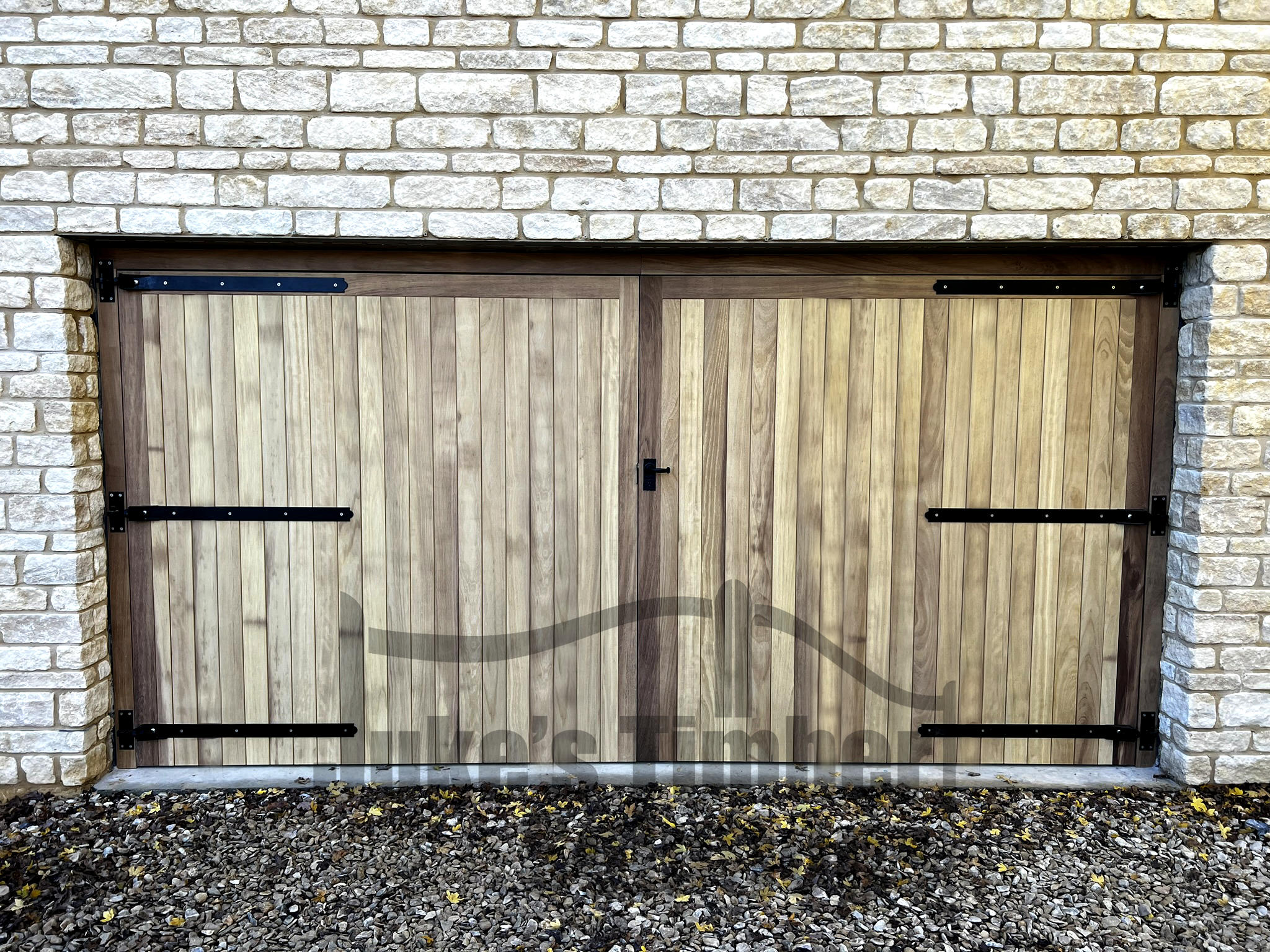 Iroko full board garage doors installed into stone building