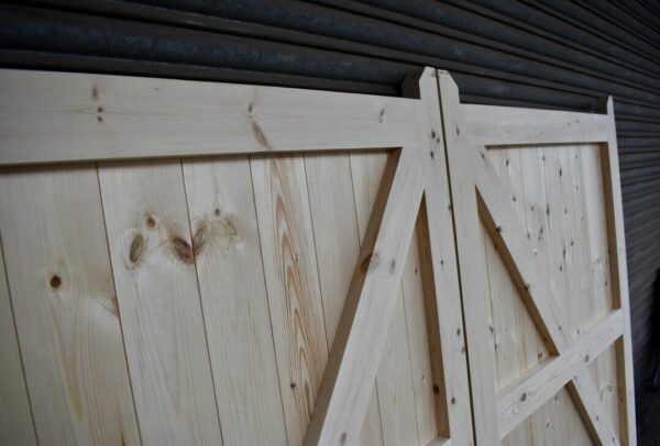 Interior detailing of a set of wooden driveway gates, showing framing, ledging and bracing. Gates leaning against metal shutters.