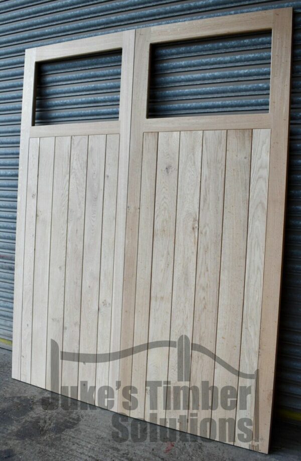 Oak single pane framed, ledged and braced garage doors pictured outside, leaning against metal shutters