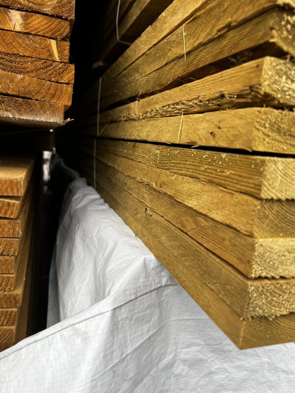 Lengths of tanalised rough sawn timber batons, bundled in packs in wood yard.