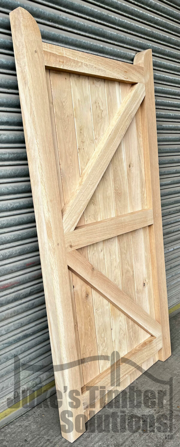 Rear of an oak flat top side gate, leaning against a metal shutter