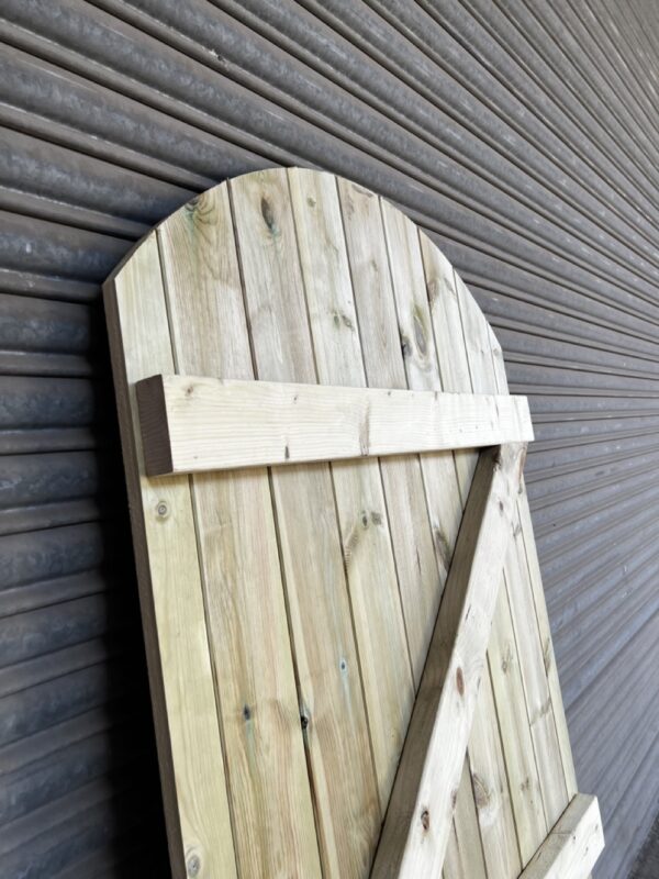 Rear of a tanalised matchboard garden gate, placed in front of a metal shutter