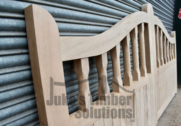 Close up of the left hand side of a oak swan neck palisade driveway gate set