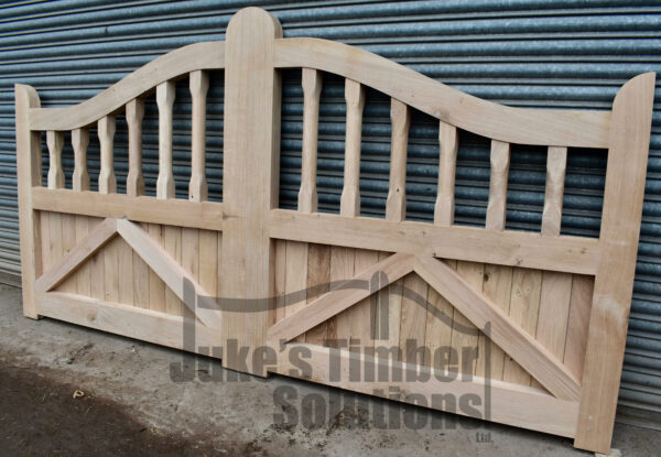 Wooden oak swan neck palisade driveway gates leaning against metal shutters