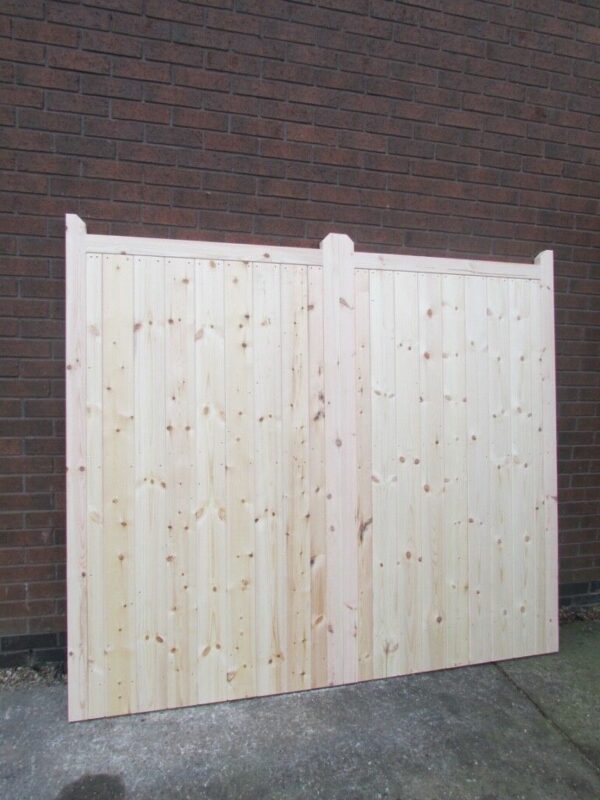 A wooden driveway gate pictured outside, leaning against red brick wall.