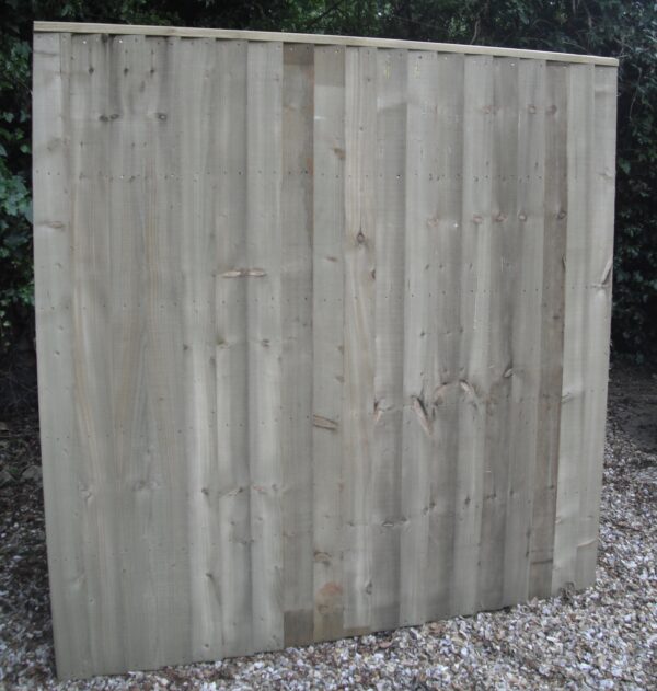 Heavy duty wooden fence panel, stood in gravel in garden.