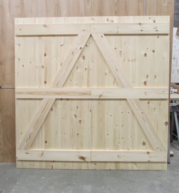 Back of a ledged and braced garage door, pictured in Juke's Timber Solutions workshop in front of wooden partition.