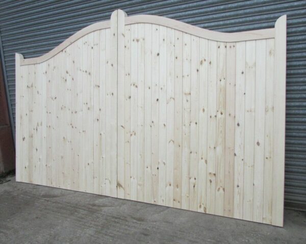 Wooden softwood swan neck driveway gates, leaning against metal shutters