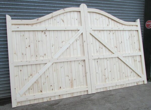 Softwood swan neck driveway gates, showing morticing and tenoning leaning against metal shutters