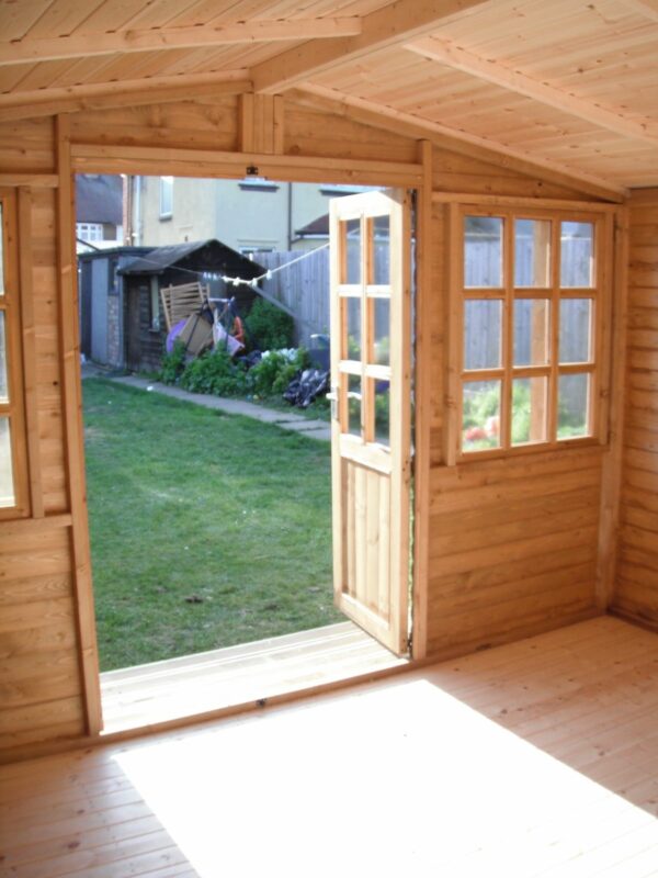 Interior of a wooden 12ft x 12ft summerhouse, looking out into a garden