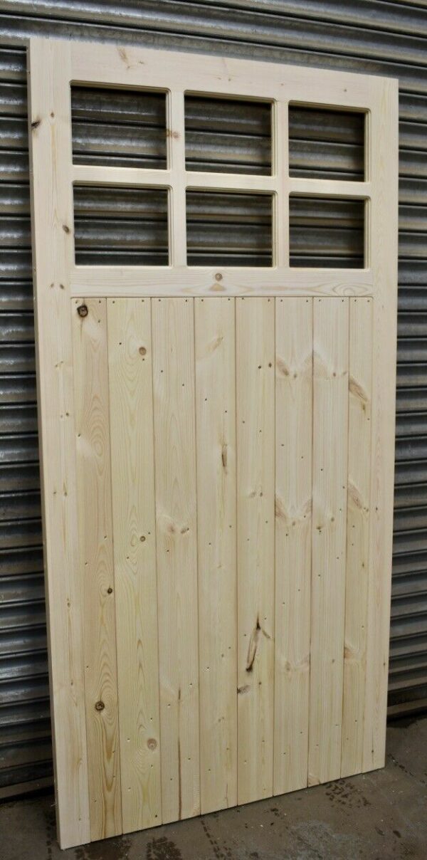 Wooden heavy duty side garage door leaning against metal shutters