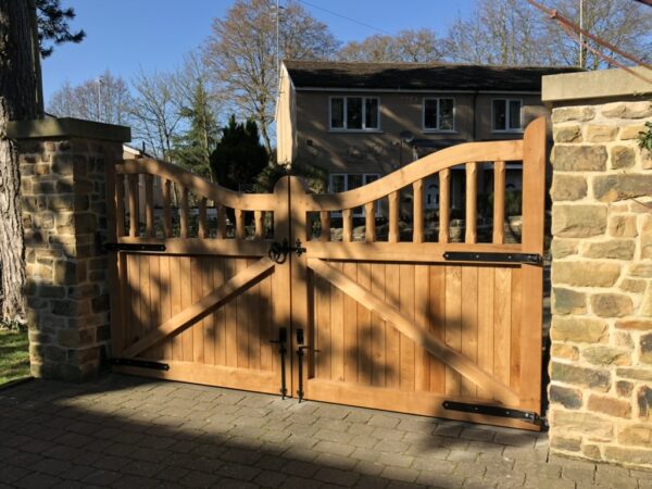 Interior of wooden driveway gates installed onto stone pillars and block paved driveway